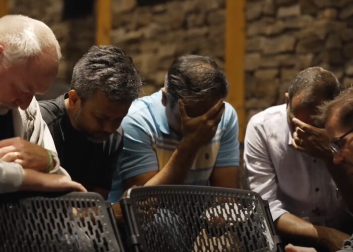 Men praying with their head in their hands