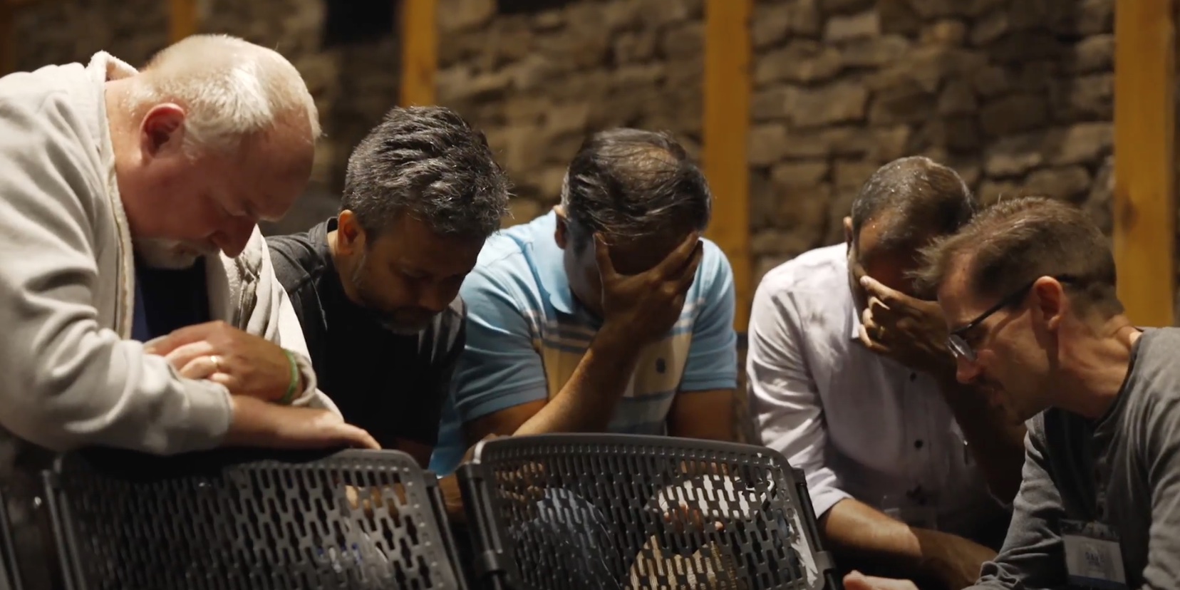 Men praying with their head in their hands