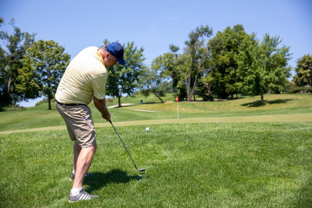 Man chipping a golf ball on the green during a No Regrets ministry golf event